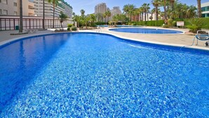 Una gran piscina al aire libre rodeada de palmeras y edificios modernos.