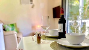 A dining table with a bottle of wine, two wine glasses, a salt and pepper shaker, and a white bowl on a woven placemat.