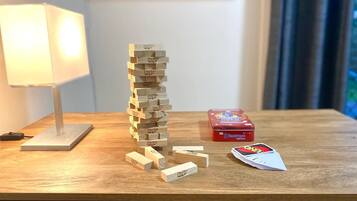 Een houten Jenga-toren op een houten tafel met een lamp en een doos Jenga-kaarten.