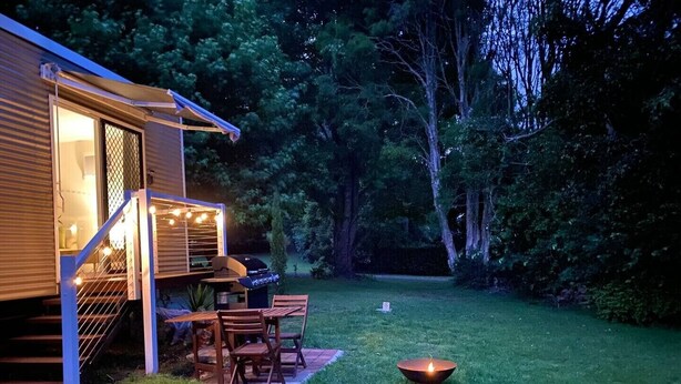 A backyard with a wooden deck, a grill, and a dining area with chairs.