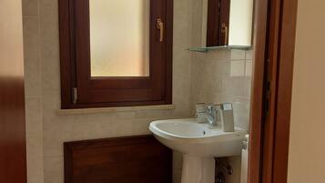 A bathroom with a toilet, sink, and mirror.