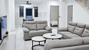 Ein modernes Wohnzimmer mit einer Eckcouch, einem runden Couchtisch und einem Fernseher auf einem Schrank.