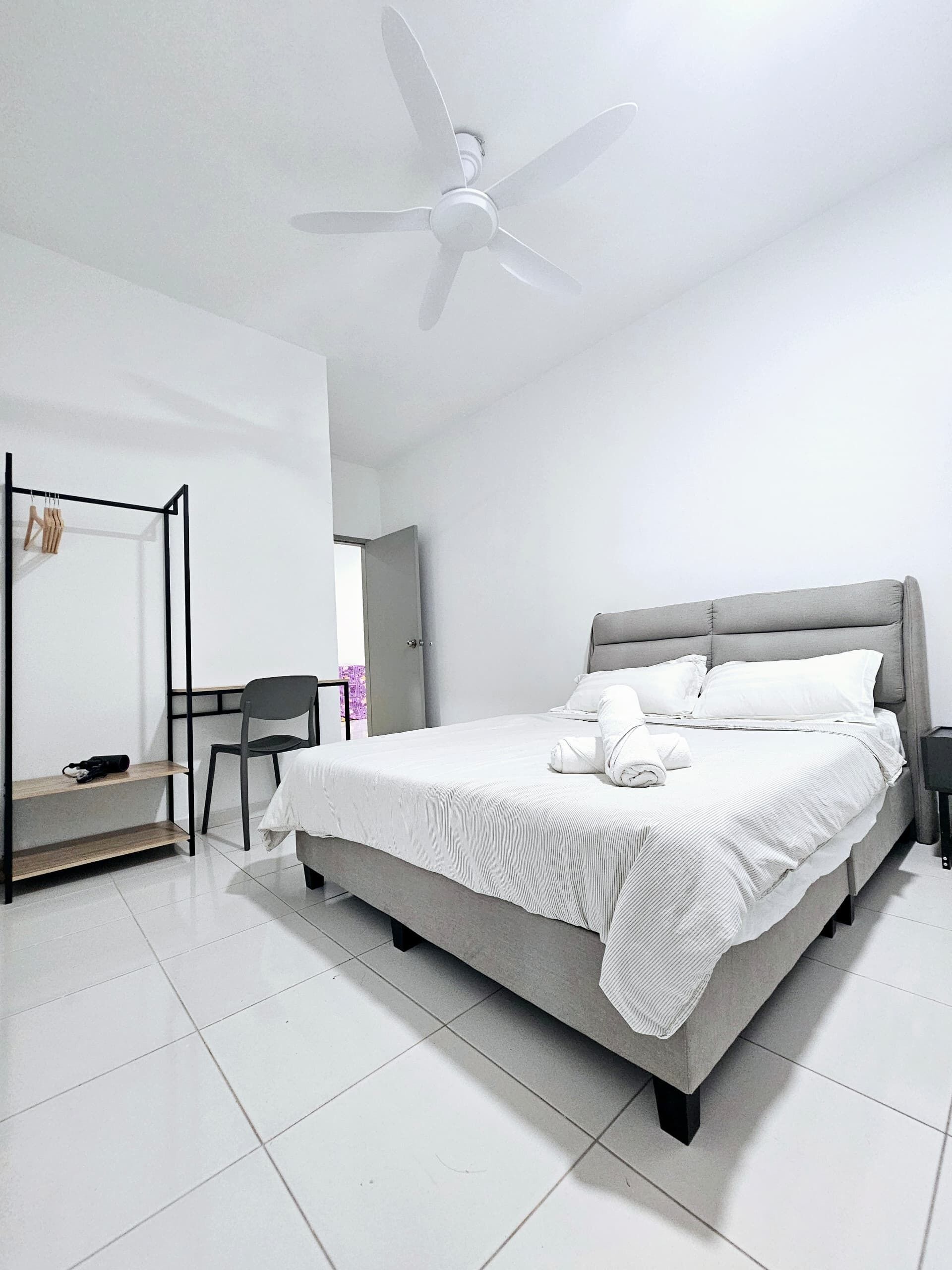 A modern bedroom with a bed, a chair, a coat rack, and a ceiling fan.