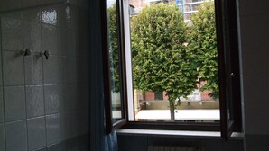 Un baño con ventana, radiador y pared de azulejos.