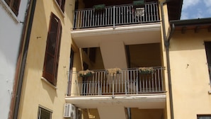 Un edificio de varios pisos con balcones, unidades de aire acondicionado y jardineras con flores.