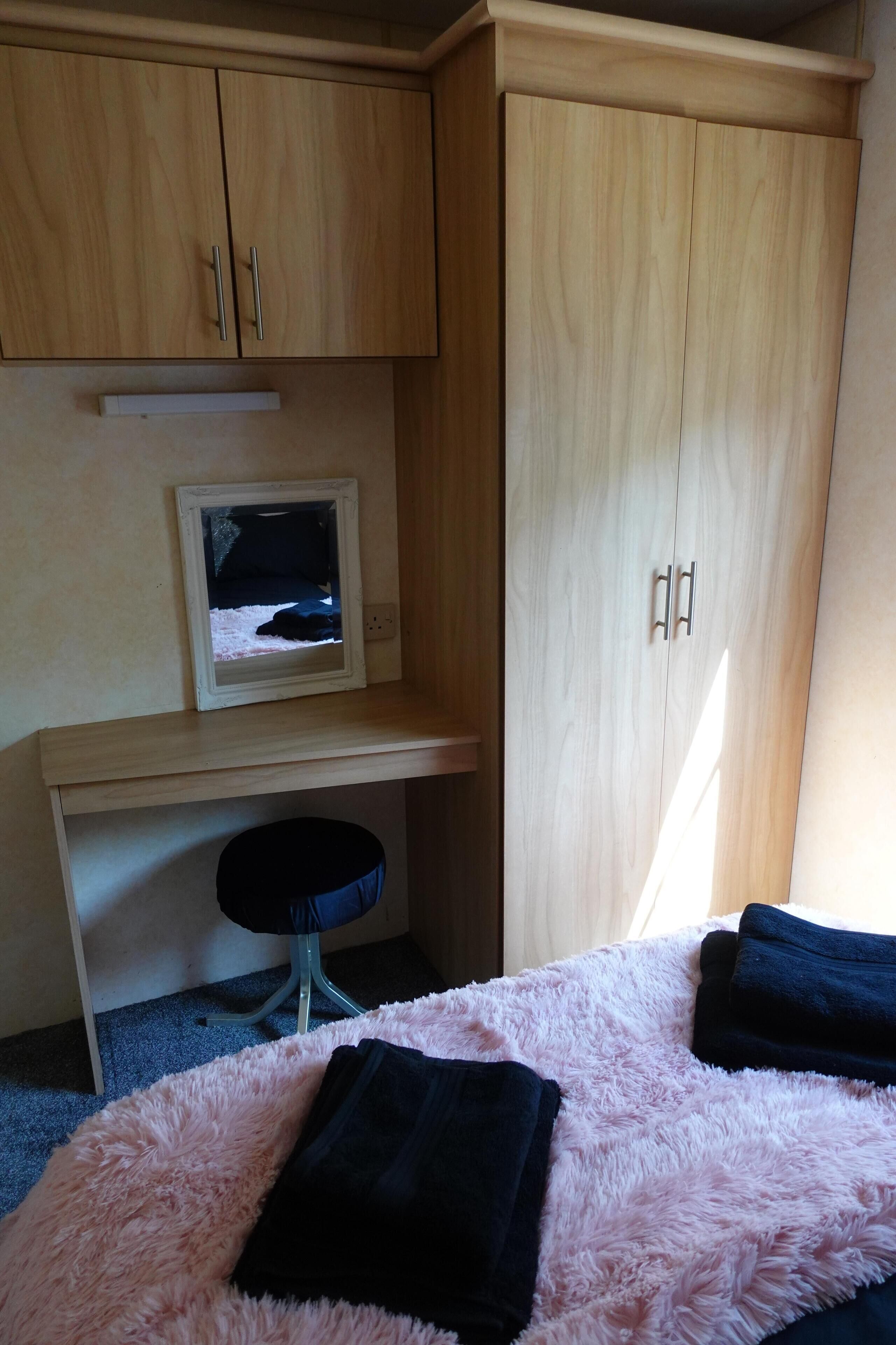 A bedroom with a bed, a desk, a chair, and a wardrobe.