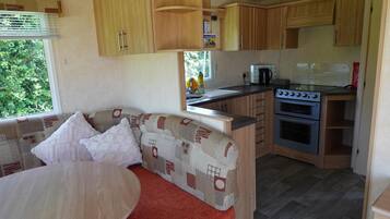 A compact kitchen with wooden cabinets, a stove, and a dining area with a sofa and table.