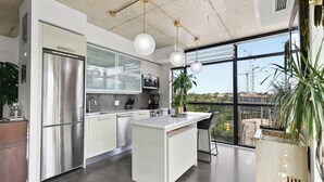 A modern kitchen with a large island, stainless steel appliances, and a view of the city through large windows. - Gsuite Express Downtown Toronto (Toronto)
