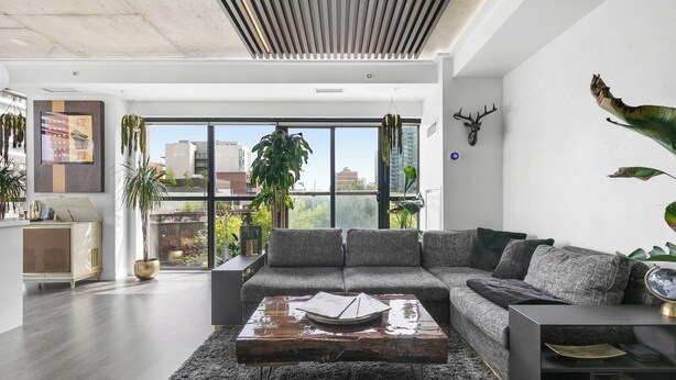 A modern living room with a sectional sofa, a coffee table, and a large window offering a city view. - Gsuite Express Downtown Toronto (Toronto)