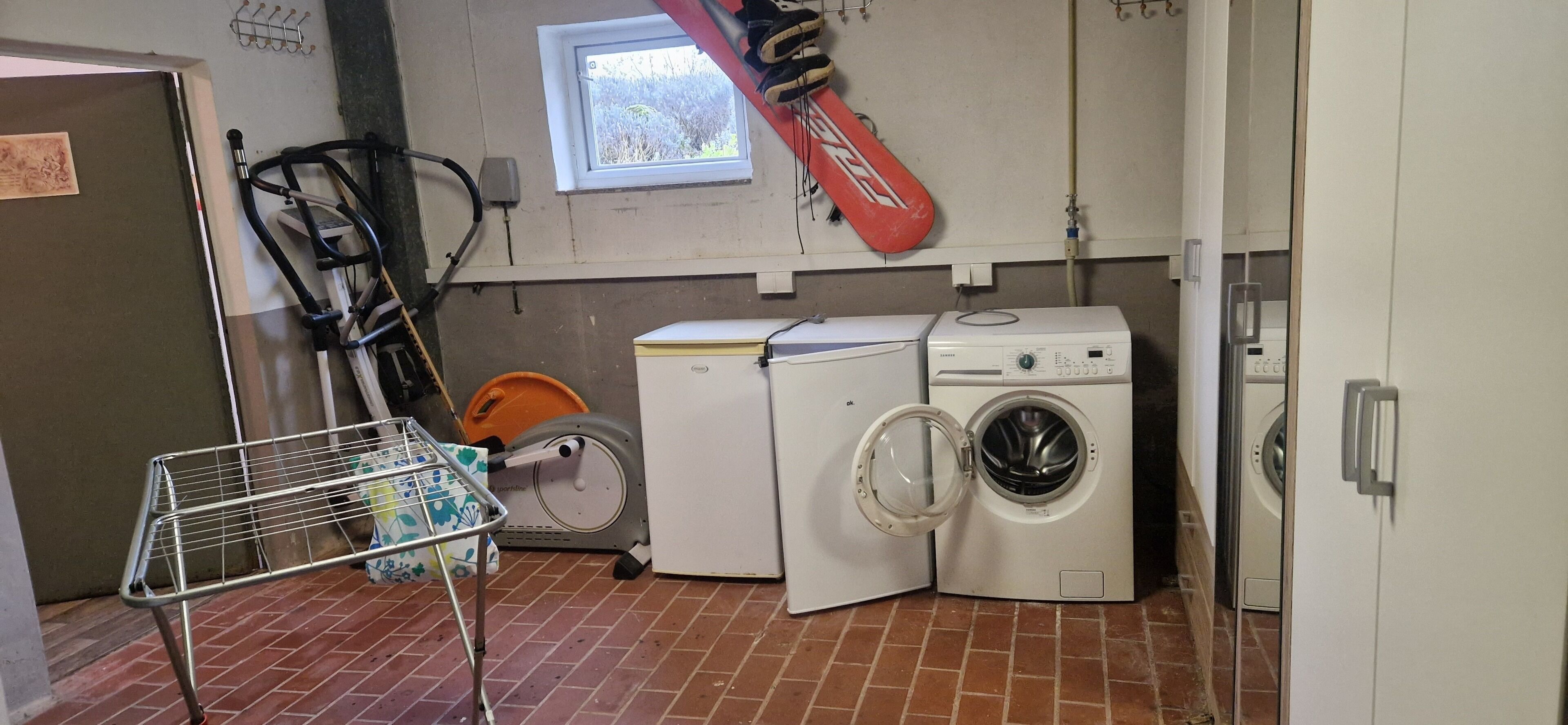 A laundry room with a washing machine, dryer, and a drying rack.