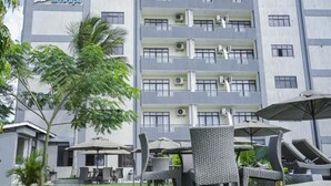 Un hotel con varios balcones, mobiliario exterior con sombrillas y un césped bien cuidado.
