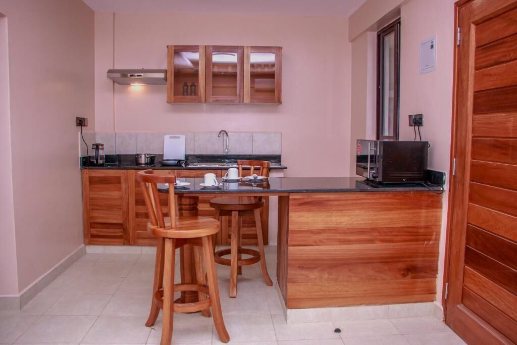 Una cucina compatta con mobili in legno, un piano di lavoro nero e un'area pranzo con sgabelli.