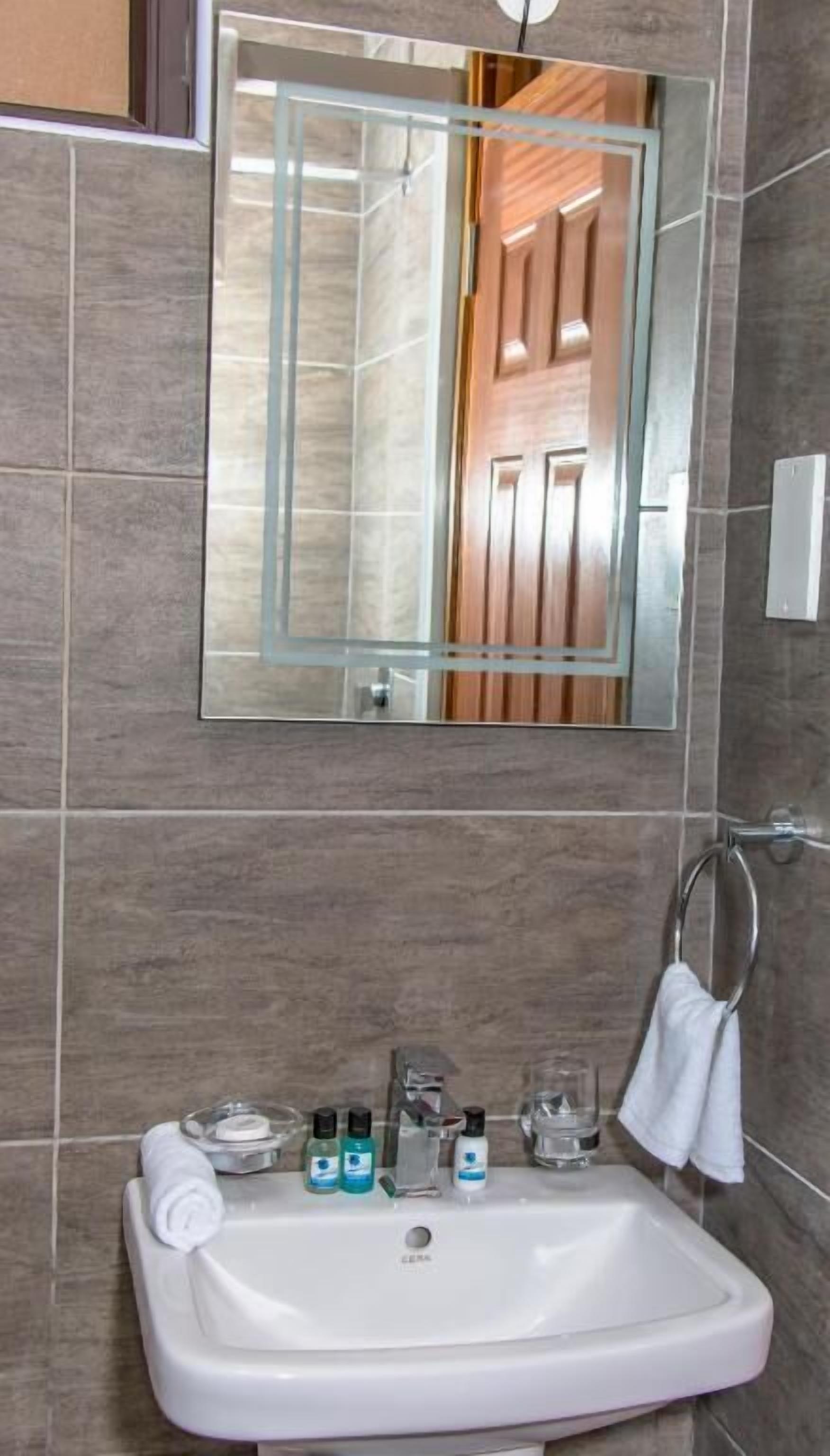 Een badkamer met een wit wastafelmeubel, een spiegel en toiletartikelen.