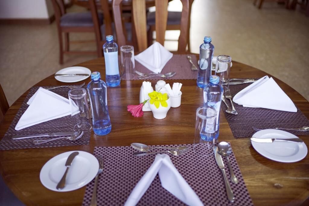 Uma mesa de jantar posta com pratos, talheres, guardanapos e garrafas de água.