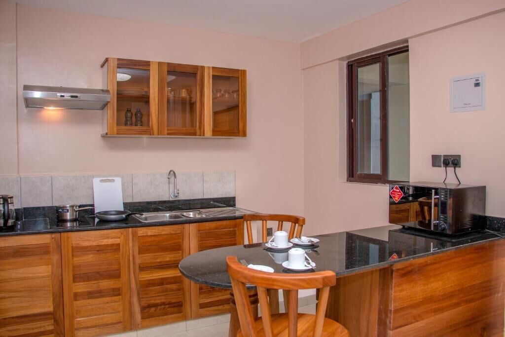 A compact kitchen with wooden cabinets, a built-in microwave, and a dining area with a table and chairs.