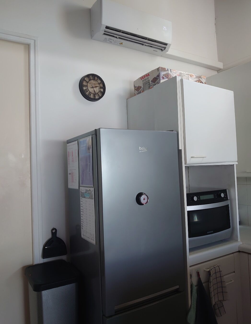 Une cuisine équipée d’un réfrigérateur, d’un four et d’une horloge murale.