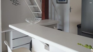 A kitchen with a white countertop, a refrigerator, and a staircase leading to another room. - Quiet, small garden, 5-minute bike ride to beaches, historic center, Hérault river (Agde)