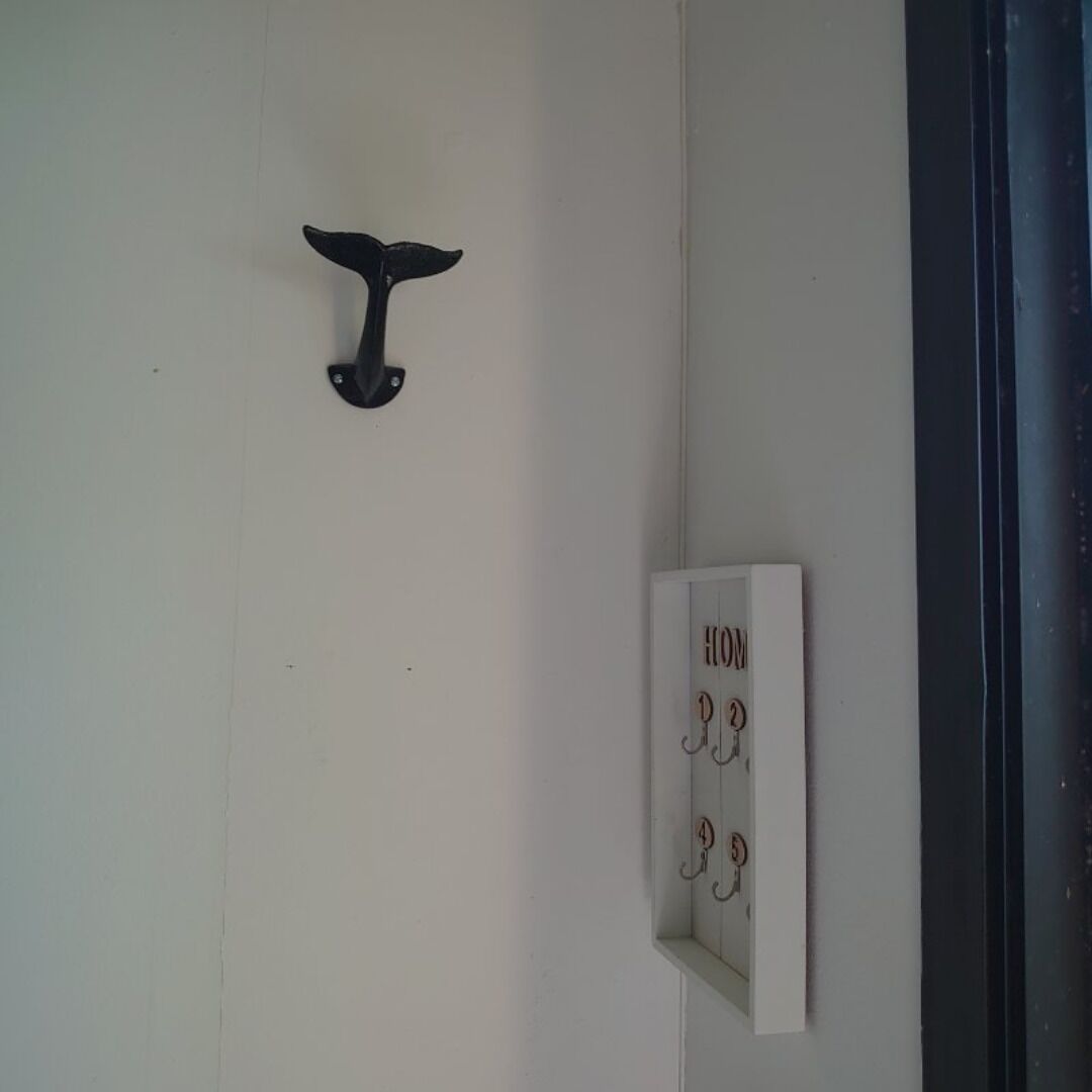 Une porte dotée d’une poignée noire en forme de baleine et d’une plaque blanche portant les chiffres de 1 à 5.