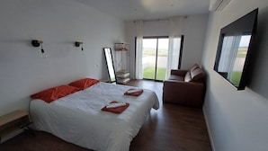 Ein Hotelzimmer mit einem großen Bett, einem Sofa, einem Fernseher und einem Balkon mit Blick.