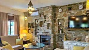 Una sala de estar acogedora con chimenea de piedra, asientos cómodos y un televisor de pantalla plana sobre ella.