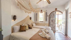 Un dormitorio con dos camas, una hamaca colgante y vistas al exterior.