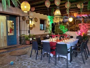 An outdoor dining area with stone flooring, wicker chairs, and tables set for a meal. - 7 Bed Villa - Sleeps 14 - Pool - Hottub - Parking (Sayalonga)