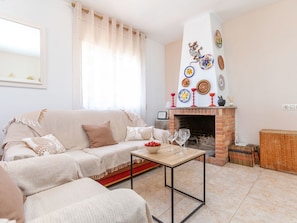 A living room with a sofa, a coffee table, a fireplace with decorative plates, and a bookshelf.