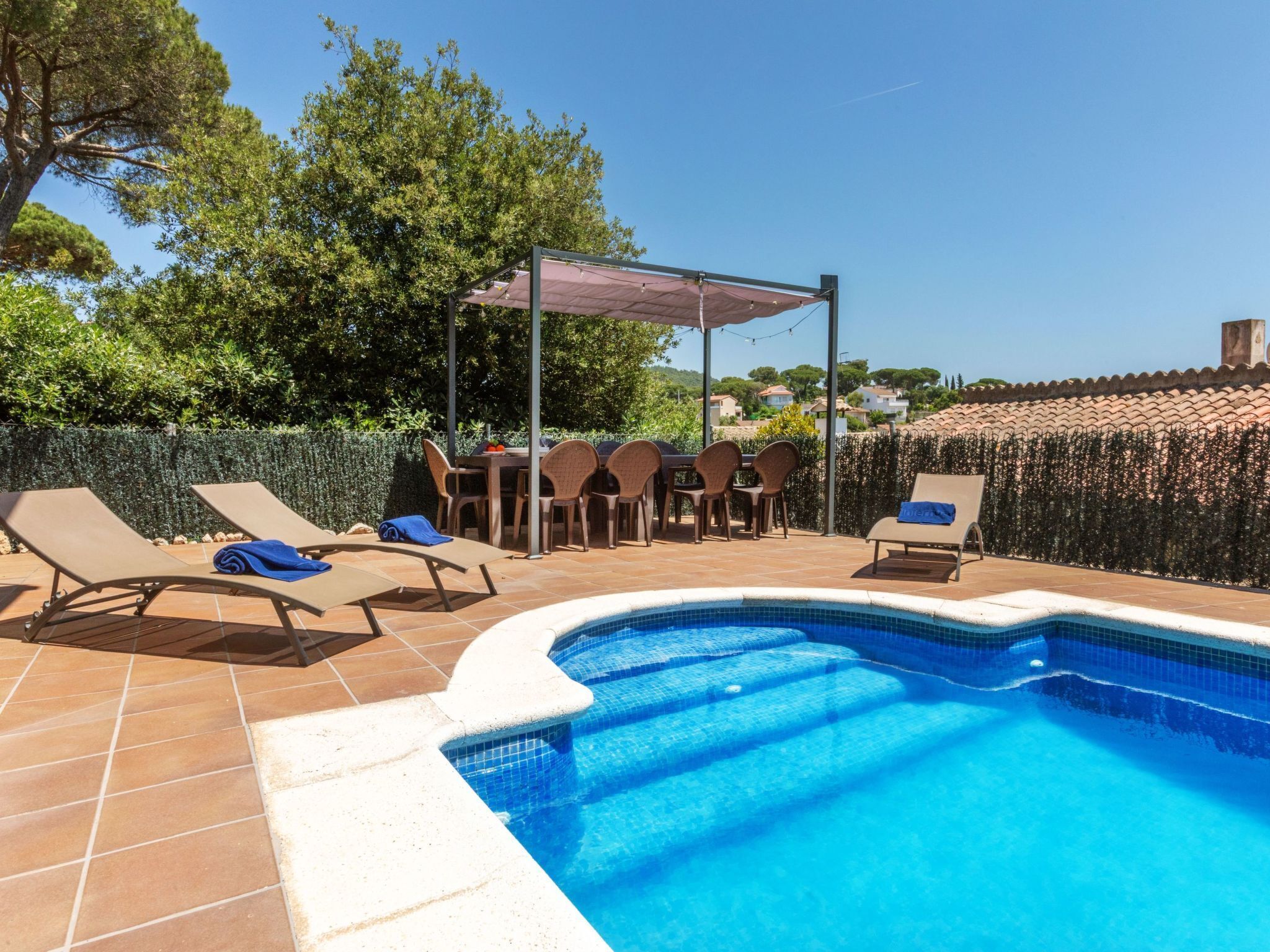 Une piscine avec des chaises longues et un espace salon abrité.