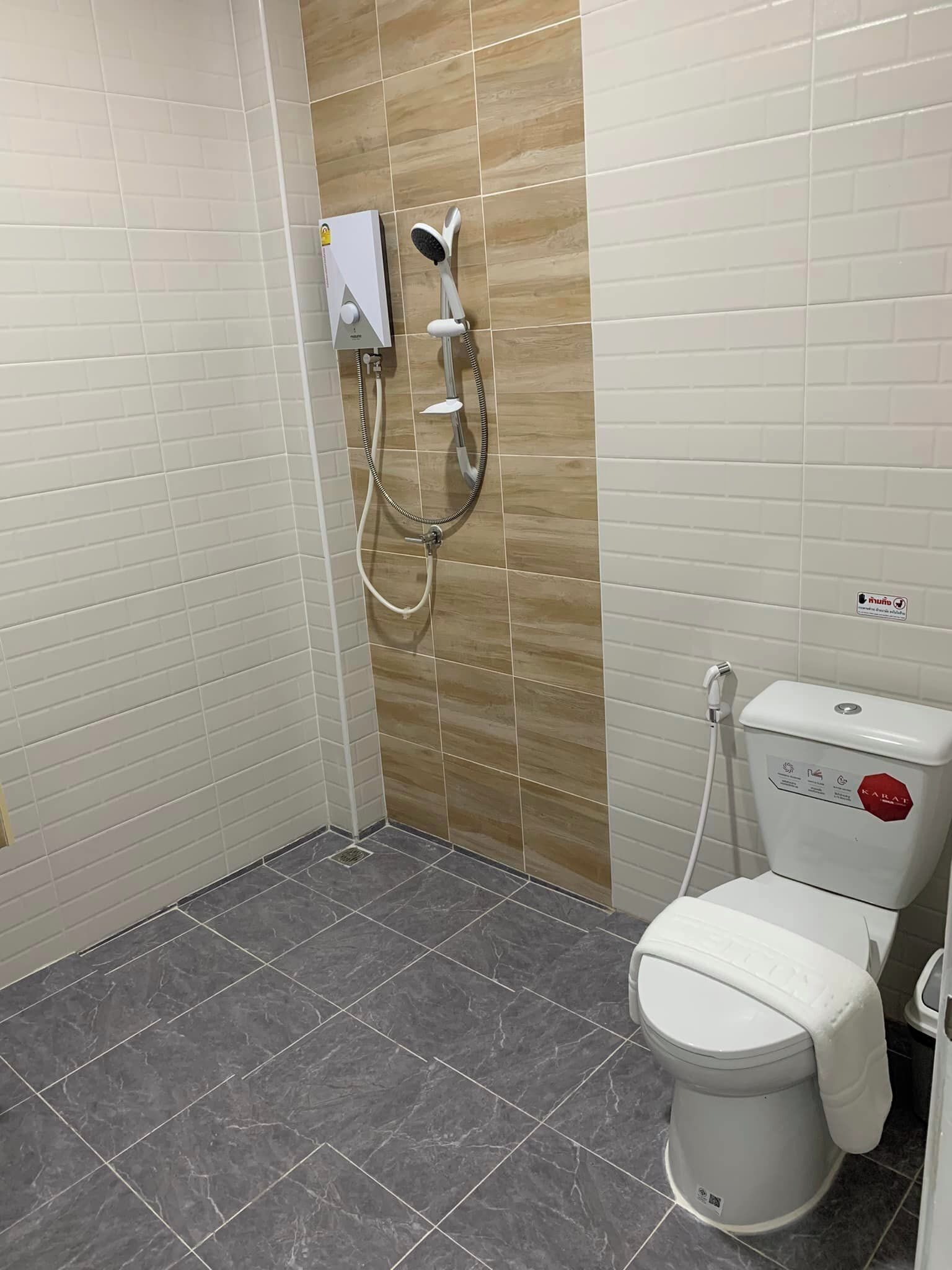 Een badkamer met een toilet, een douche en een toiletrolhouder.