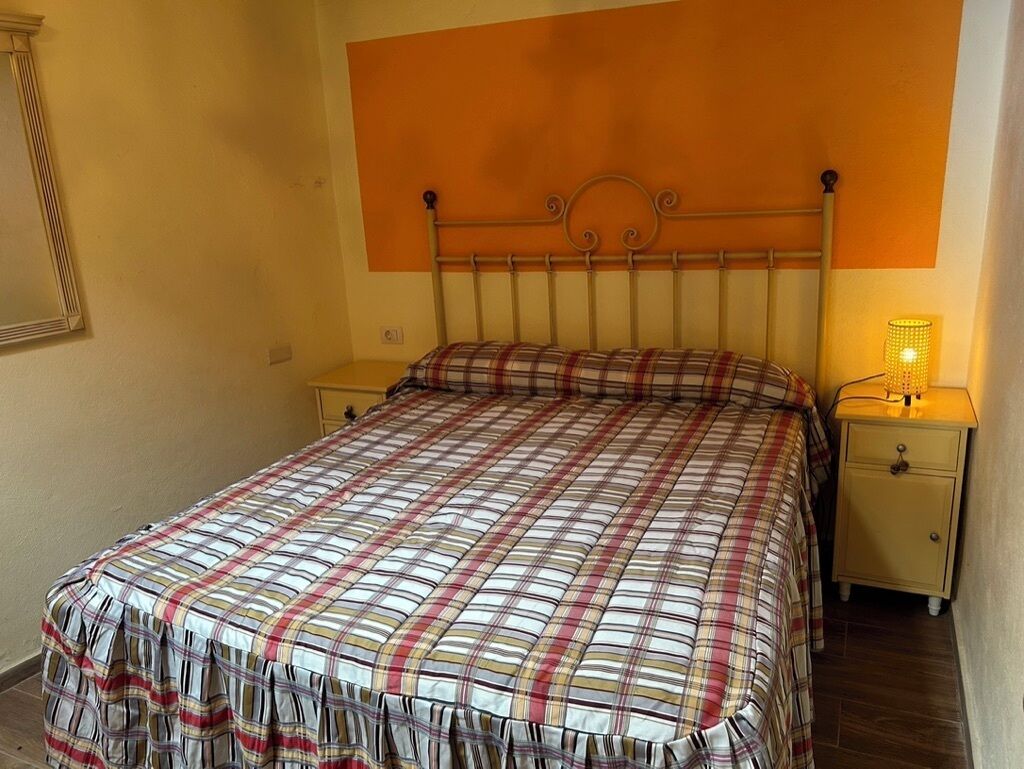 Une chambre à coucher avec un lit, des tables de chevet et une lampe.