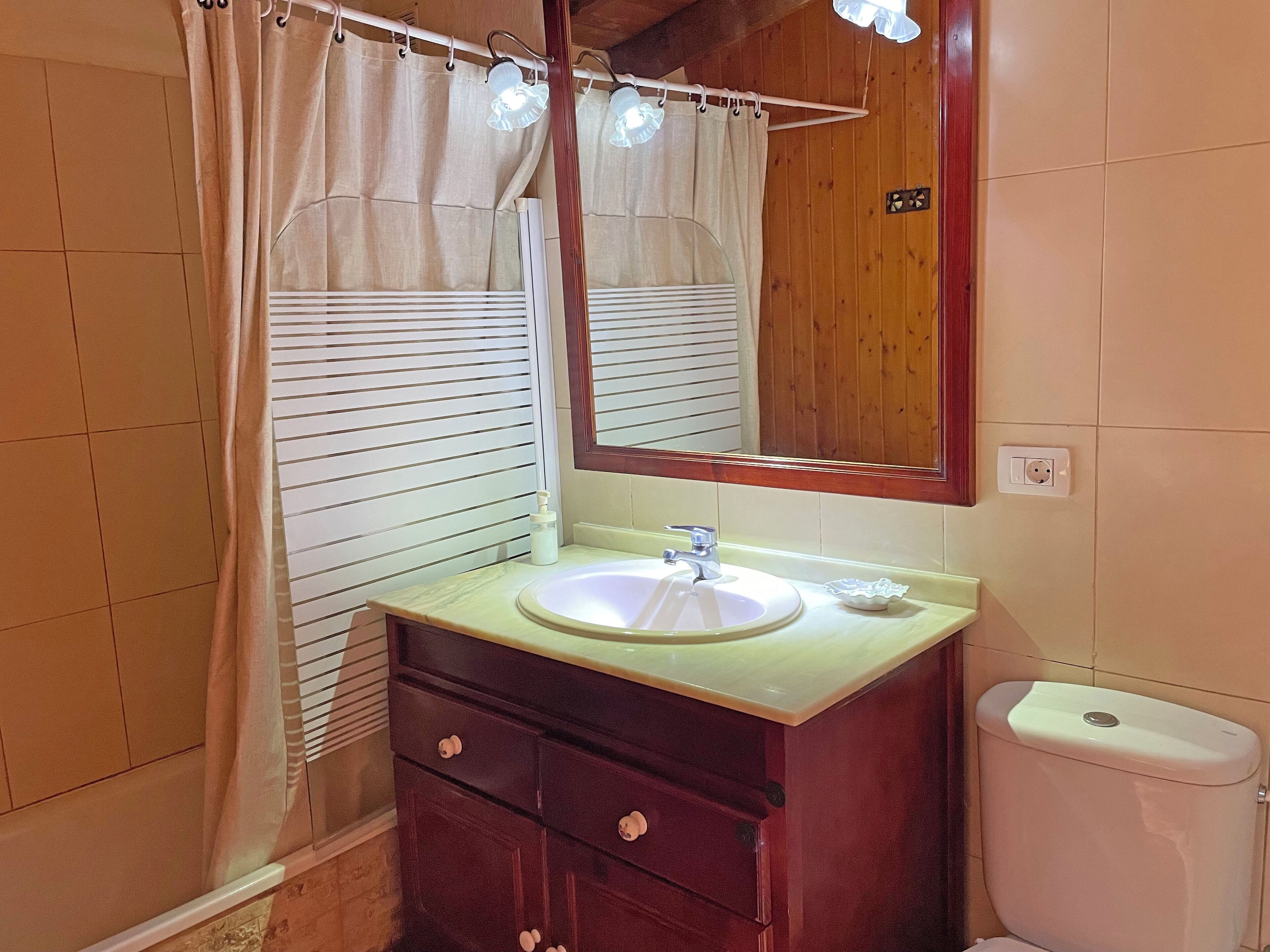 A bathroom with a sink, mirror, vanity, and toilet.