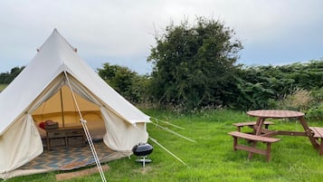 A tent with a picnic table and a grill outside.