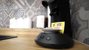 Une machine à café avec une carte insérée, une cafetière et un mur à motifs en arrière-plan.
