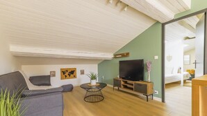 Un salon moderne avec un canapé gris, une table basse ronde, un téléviseur à écran plat et un meuble en bois.