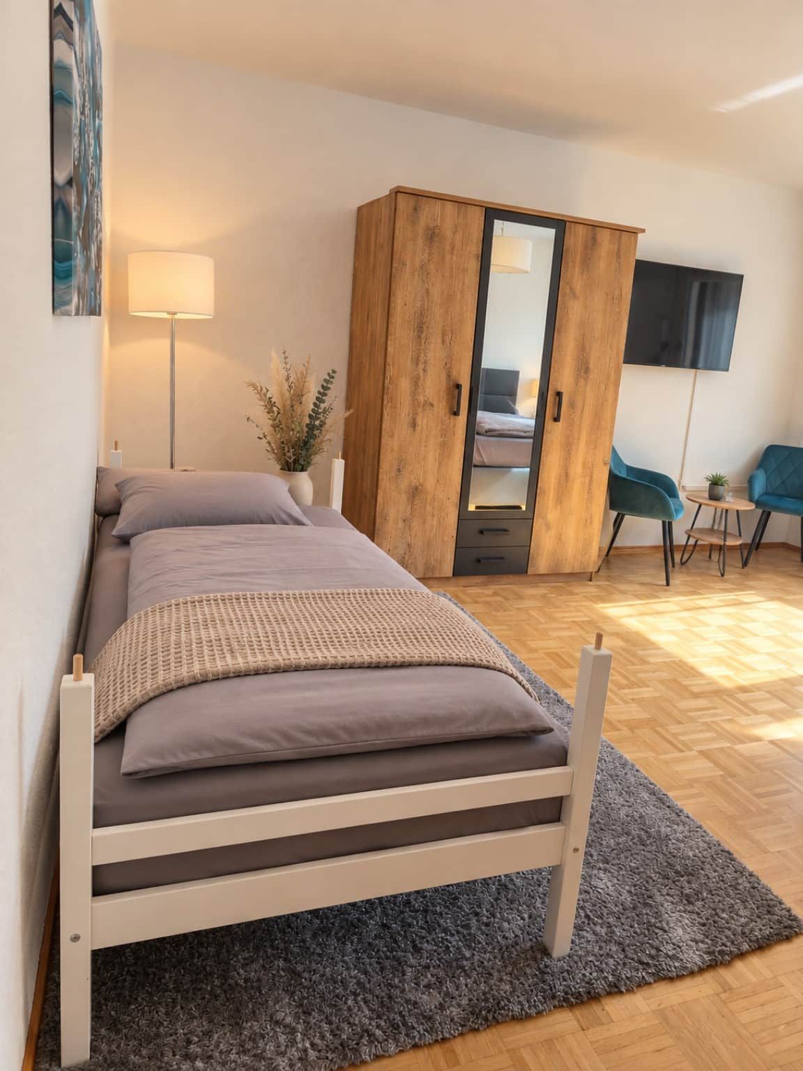 Ein Schlafzimmer mit einem Bett, einem Kleiderschrank, einem Fernseher und einem kleinen Tisch mit Stühlen.