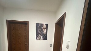 Ein Flur mit zwei Holztüren, einem Kachelboden und einem an der Wand befestigten Lichtschalter.