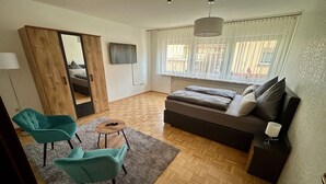 Ein modernes Wohnzimmer mit einer Couch, zwei Sesseln, einem kleinen Tisch und einem großen Spiegel.