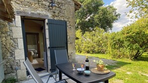 Un edificio in pietra con una porta in legno, un tavolo con una bottiglia di vino, bicchieri e una ciotola.