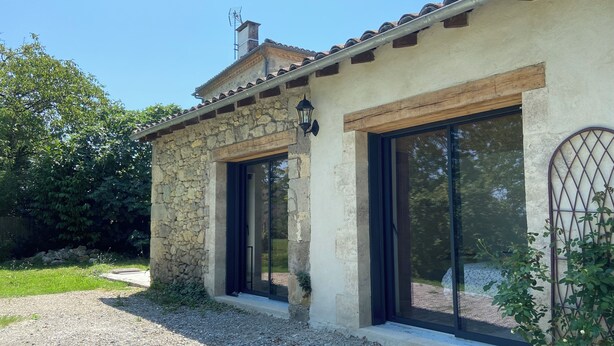 Un edificio in pietra con ampie vetrate e un tetto in tegole.