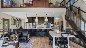 Un'ampia cucina con isola centrale, posti a bar e una scala che conduce a un piano superiore.