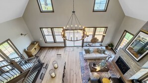 Spazioso loft con soffitto alto, ampie finestre, un tavolo da pranzo in legno al centro, un camino e una scala.