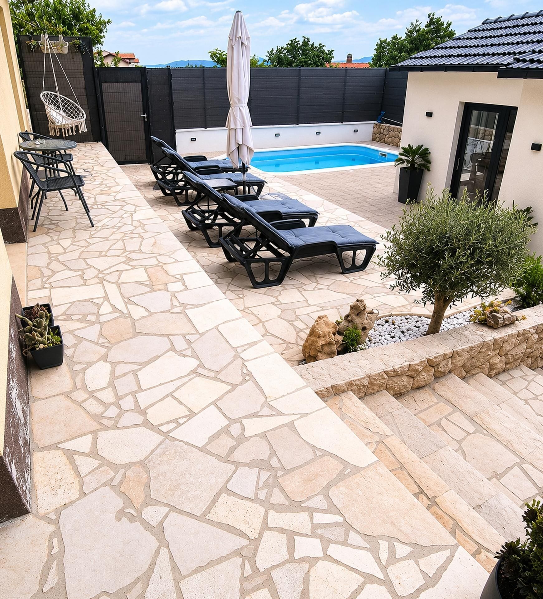Uma área de piscina com espreguiçadeiras e um terraço de pedra.