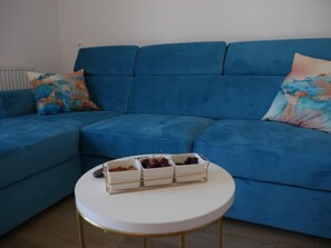 A blue sofa with a white coffee table in front, and a small white table with a fruit tray. - Aparment With Private Pool ,shades of Bluemm (Imotski)