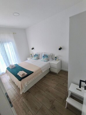 A bedroom with a bed, nightstands, a bedside table, a window with curtains, and a wooden floor. - Aparment With Private Pool ,shades of Bluemm (Imotski)