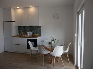 A modern kitchen with white cabinets, a marble backsplash, and a dining area with a glass table and white chairs. - Aparment With Private Pool ,shades of Bluemm (Imotski)