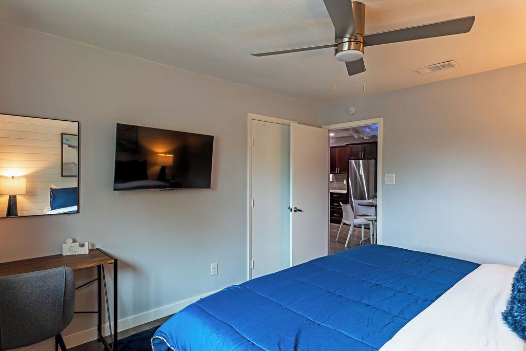 Une chambre d’hôtel équipée d’un lit, d’un bureau, d’une chaise, d’une télévision et d’un ventilateur de plafond.