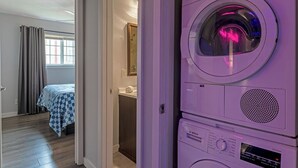 Een wasserette met gestapelde wasmachines en een bed in de aangrenzende kamer.