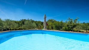 Une piscine d’un bleu éclatant, avec un poste de surveillance pour les sauveteurs en arrière-plan, le tout entouré d’une végétation luxuriante.