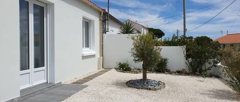 Een modern huis met een grindpad, een kleine boom en een witte gevel.