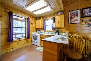 Cocina de estilo rústico con paredes de madera, una isla central y una mesa de comedor con sillas.